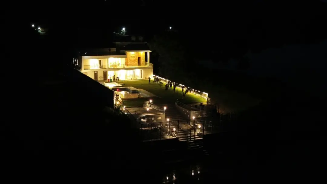 A lit house on a dark hillside at night