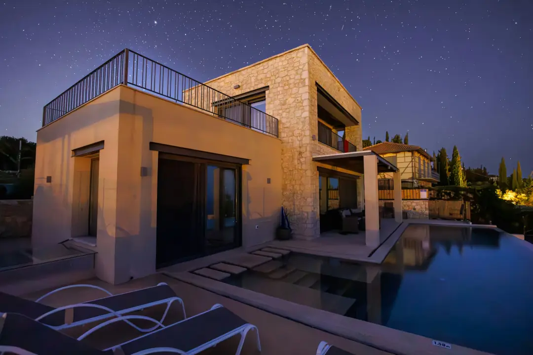 A stone residence with an infinity pool under a night sky